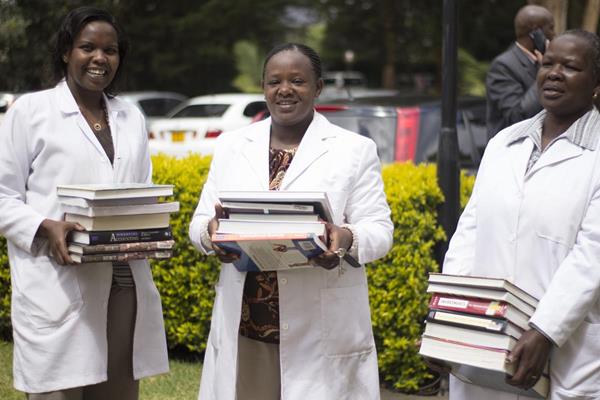 Medical students at St. Paul's University in Kenya show off new books from a BFA shipment