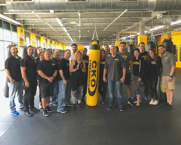 CKO member and Humanitarian Award recipient, Lauren Mortenson poses holding her award with the CEO of CKO Kickboxing, the corporate staff, and the company's Franchisee Advisory Council.