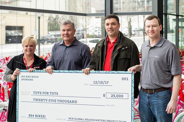 Team members from NCR, JLL, and HITT Contracting present the Atlanta chapter of Toys for Tots with $25,000 in addition to all the bikes donated.