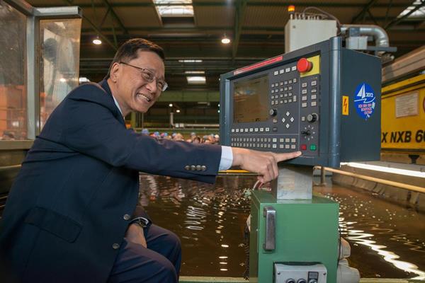 Tan Sri Lim Kok Thay pushes the button to start the first steel cut