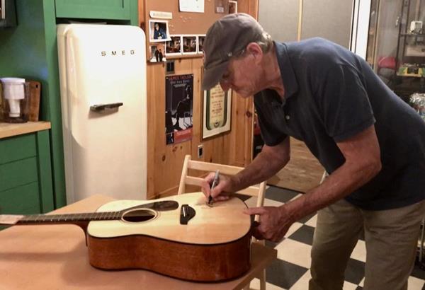 James Taylor signing a guitar for CURE's online charity auction.