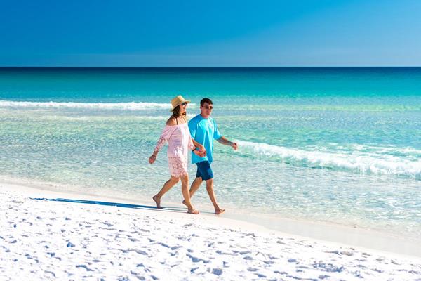 A couple enjoys a walk along the soft sand beaches of Destin, Florida as part of a Valentine's Day beach getaway.