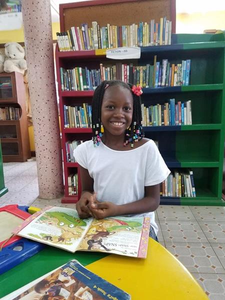 A student in Sierra Leone enjoys new reading materials delivered by a partnership between Books For Africa and Sierra Leone Book Trust
