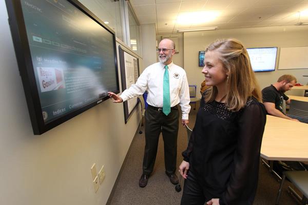 J. Douglas Wellington, JD, LLM, an associate professor in Husson’s School of Business and Management helps explain investment concepts to student Kimberly L. Boyle at the university’s Ronan Center for Financial Technology. (2015) Shortly after this photo was taken, Boyle completed her Bachelor of Science in Business Administration with a concentration in management. 