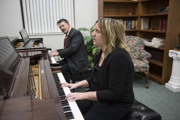 Dr. Chuck Clevenger plays a piece of music to help teach Macy McClain play the piano. Photo by Scott Huck