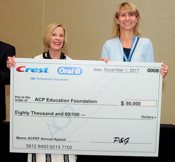ACP Immediate Past President Dr. Susan A. Brackett, left, receives a check for $80,000 from Dr. Malgorzata Klukowska from P&G Crest Oral-B.