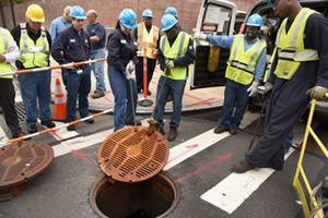Con Edison workers test a latched manhole cover