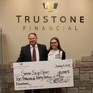 Tim Bosiacki, Chief Executive Officer at TruStone Financial, presents the donation check to Ainsley Cox, Youth Leader of the Kid Advisory Board at Simon Says Give